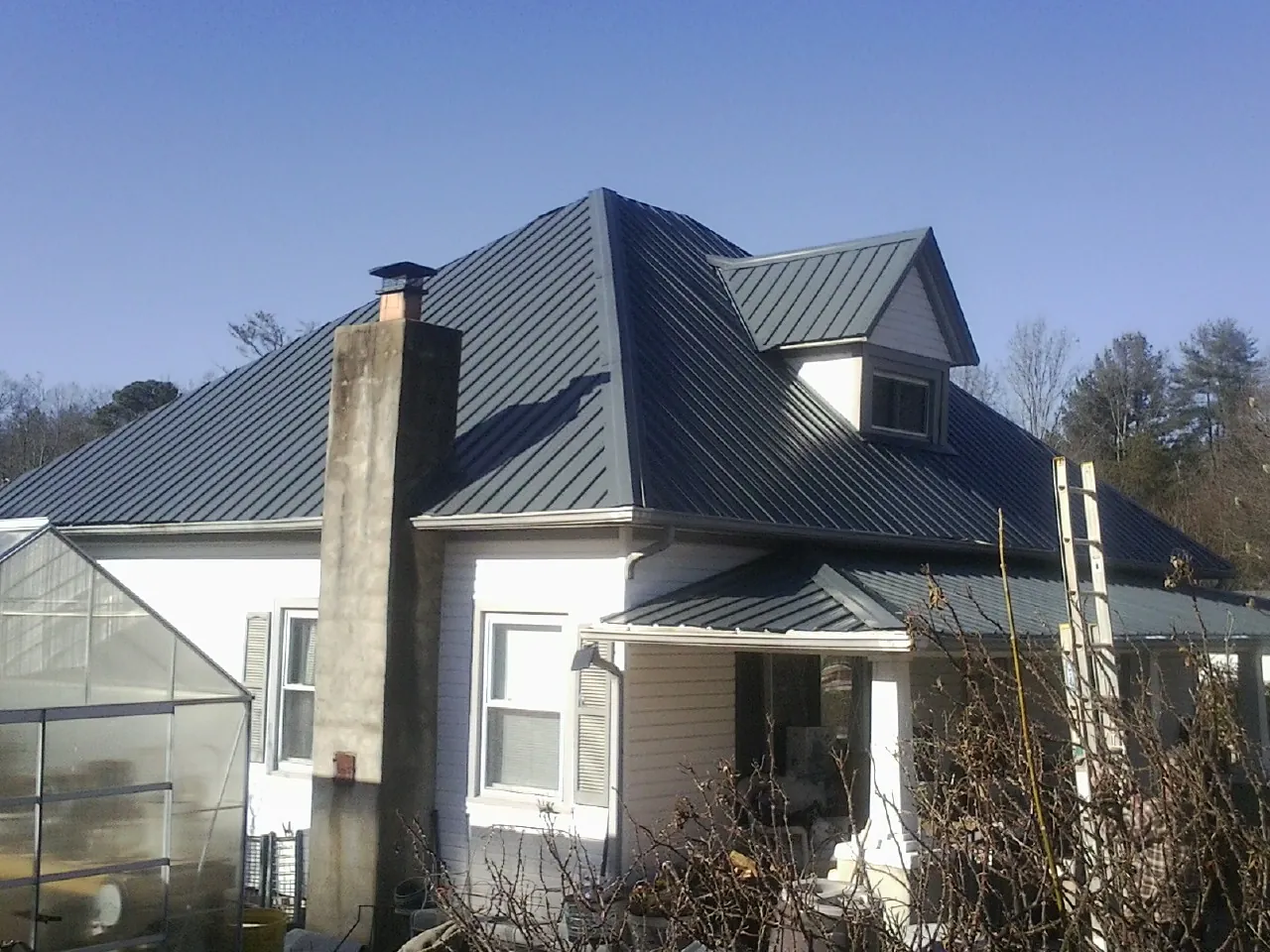 Dark blue standing seam metal roof on a white farmhouse with dormer — Slate & Tile Roof Repair by Roofing Brothers in Fort Oglethorpe