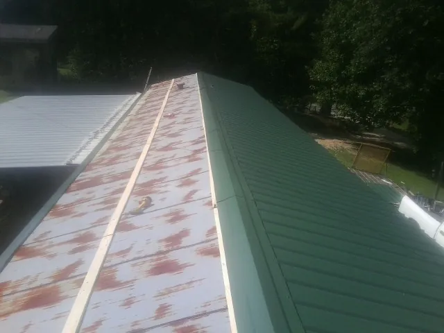 Old rusted panels beside newly installed green metal roofing — Wind Damage Roof Repair by Roofing Brothers in Fort Oglethorpe