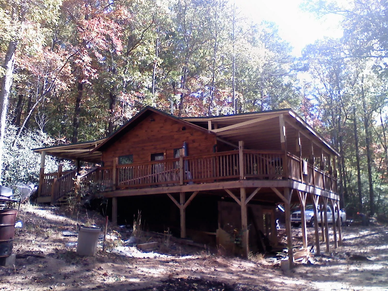 Log cabin with a wraparound porch and metal roof in the fall in Fort Oglethorpe