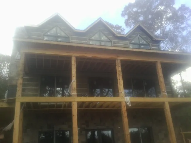Dormers and porch framing on a large log home under construction — Roof Coating work by our crew in Fort Oglethorpe