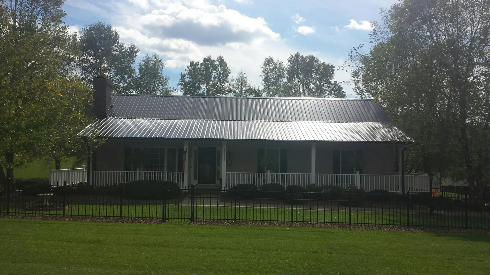 Gray metal roof on a brick ranch with a full width front porch — Gutter Guard Installation work by our crew in Fort Oglethorpe