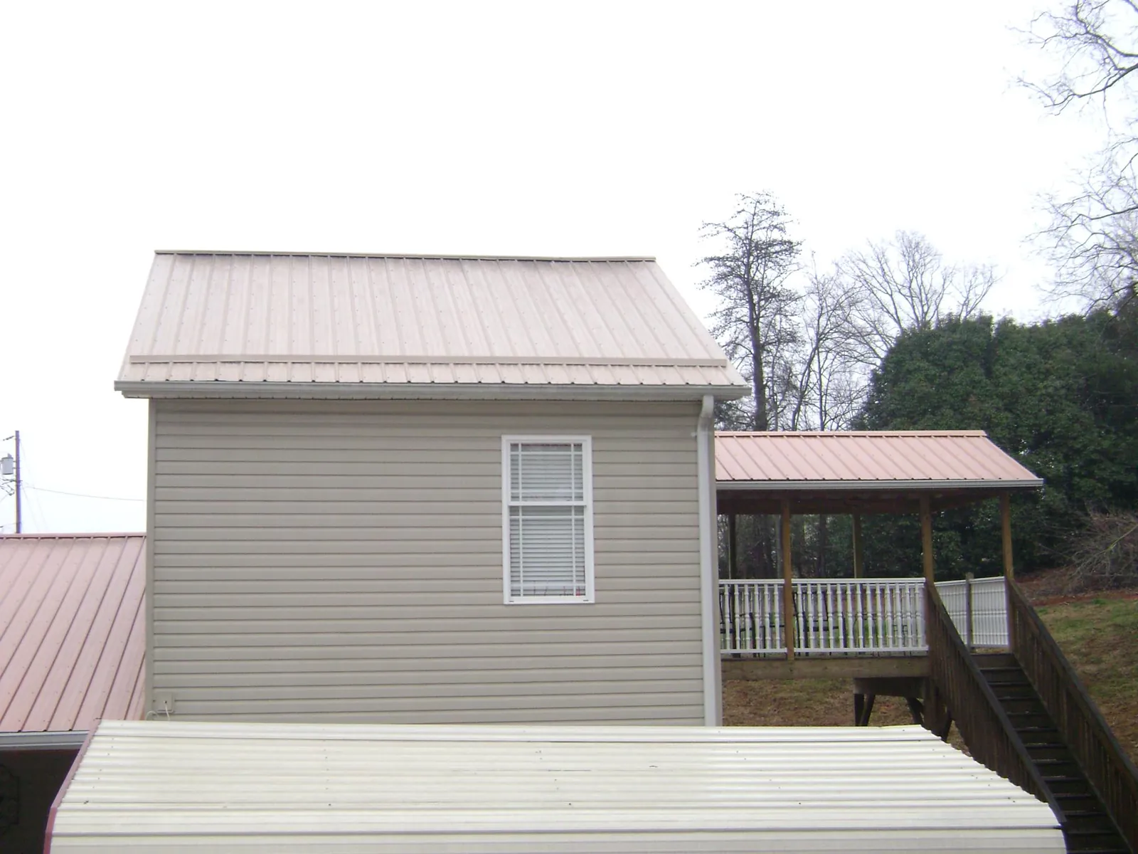 Tan metal roofs on a two story addition and attached porch, from a Roof Replacement job in Fort Oglethorpe